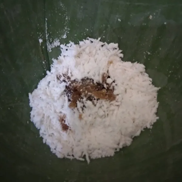 Ambil selembar daun pisang, bentuk segitiga. Beri 1,5 sdm campuran tepung, masukkan gula merah sisir ketengah tepung. Bungkus dan semat dengan lidi.