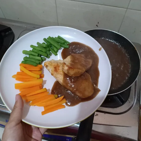Tata sayuran dan steak ayam lalu siram dengan saus lada hitam jangan lupa tambahkan jagung pipil. Sajikan selagi hangat