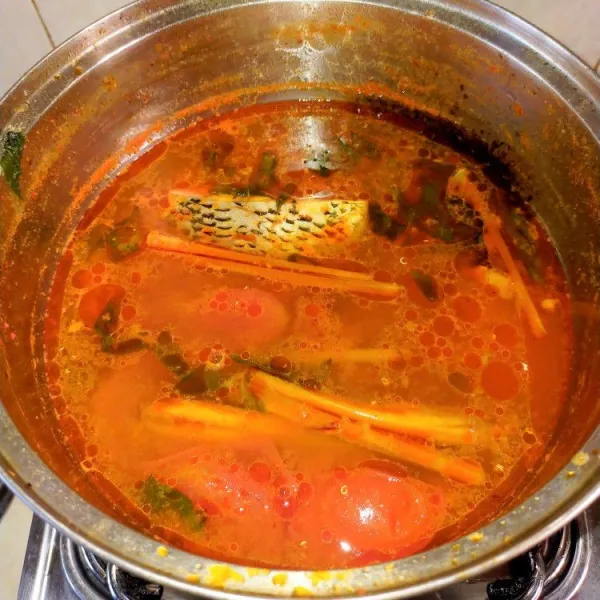 Masukkan ikan dan air. Masak hingga kuah agak mengental dan ikan hampir matang. Tambahkan garam, gula, dan tomat. Masak hingga matang. Matikan api. Masukkan daun kemangi. Adu hingga rata.