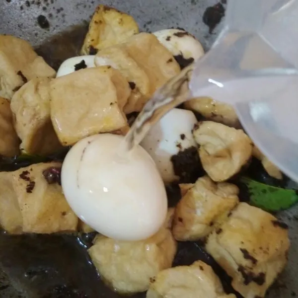 Tambahkan potongan tahu goreng dan telur rebus yang sudah dikupas kulitnya aduk hingga rata tambahkan air