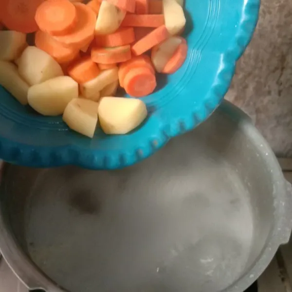 Nyalakan api kembali. Masukkan wortel dan kentang. Masak sampai setengah empuk.