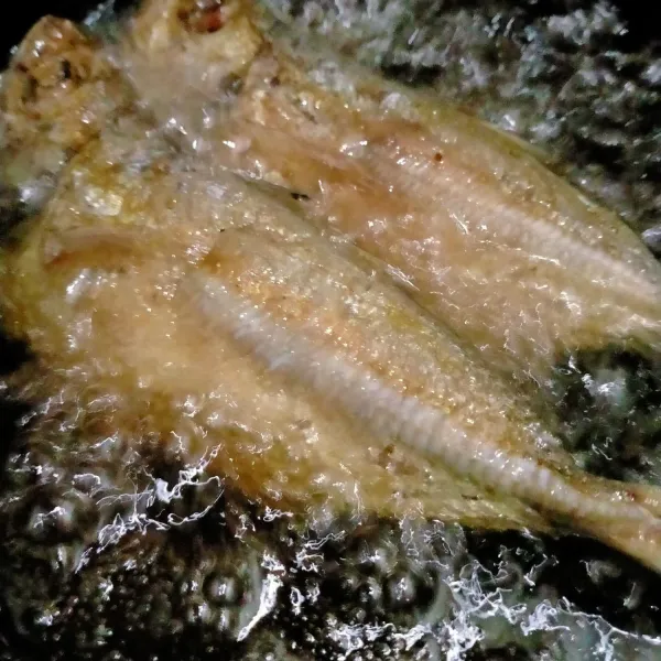 Goreng ikan kembung dalam minyak panas hingga matang.