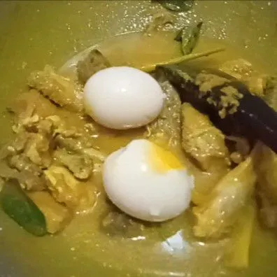 Tambahkan telur, aduk lagi hingga rata, tambahkan air. Masak hingga mendidih dan ayam meresap dengan sempurna