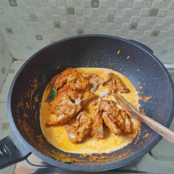 Setelah bumbu meresap masukkan santan setengah bagian kemudian masak hingga ayam setengah empuk.