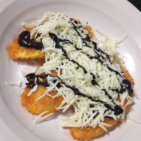 Setelah pisang matang, taburkan parutan keju dan cokelat leleh di atasnya.
