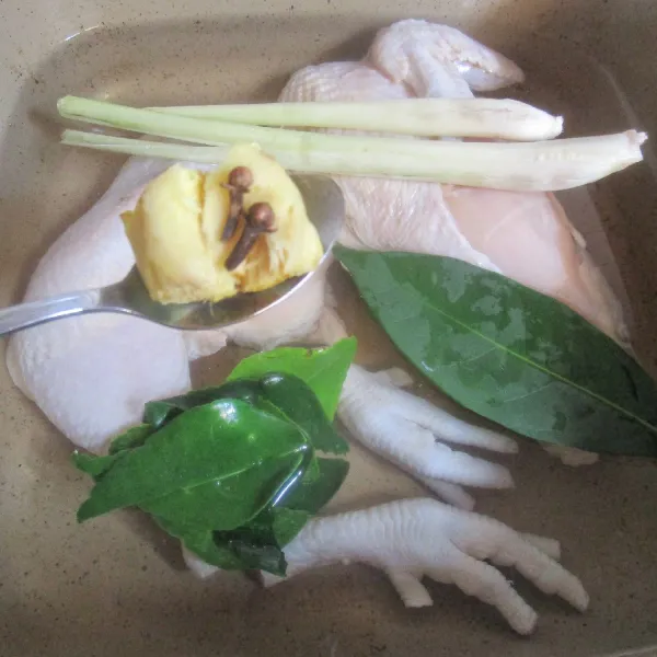 Masukkan ayam dalam panci. Tuang air. Tambahkan cengkeh, jahe geprek, serai geprek, daun jeruk dan daun salam. Rebus hingga ayam matang dan air menjadi kaldu. Sisihkan.