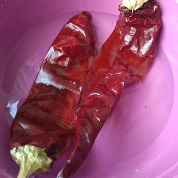 Rendam air panas cabe merah kering kemudian buang biji dan tangkainya.