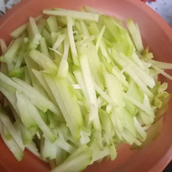 Labu siam di iris menyerupai korek api. Beri 1/2 sdt garam halus kemudian remas-remas hingga labu layu lalu cuci bersih dan tiriskan.