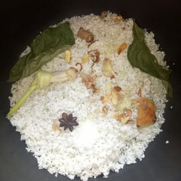 Masukkan bahan yang sudah di tumis tadi ke panci rice cooker, tambahkan garam, kaldu bubuk dan daun salam.