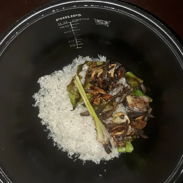 Cuci beras lalu masukkan ke dalam panci rice cooker. Tambahkan tumisan bumbu.