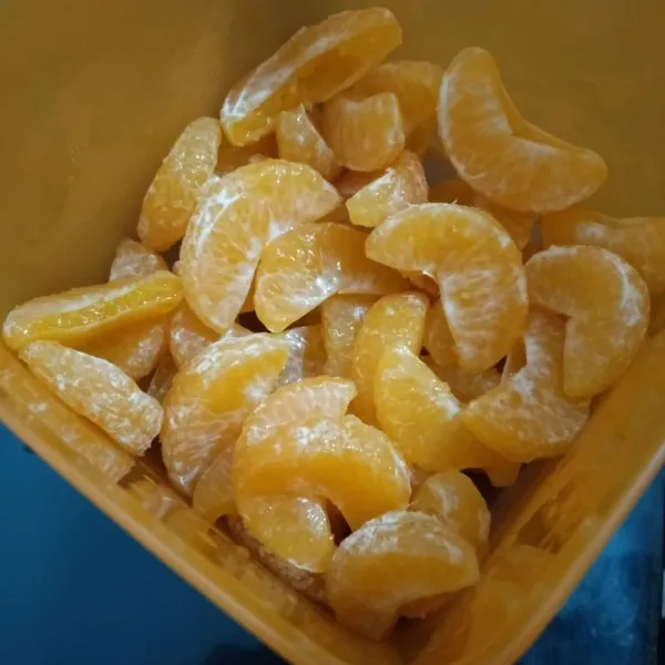 Kupas jeruk terlebih dulu. Buang biji-bijinya. Gunting di bagian lengkungannya untuk memudahkan buah bijinya.