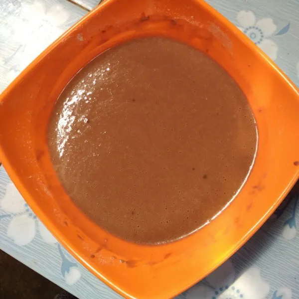 Campur tepung terigu, gula pasir, coklat bubuk, dan susu bubuk, lalu aduk rata. Tambahkan air, aduk kembali sampai licin
