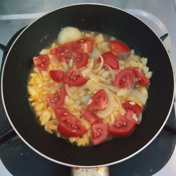 Tumis bawang putih dan bawang bombai sampai harum dan layu. Masukkan air dan tomat. Masak sampai mendidih dan tomat layu