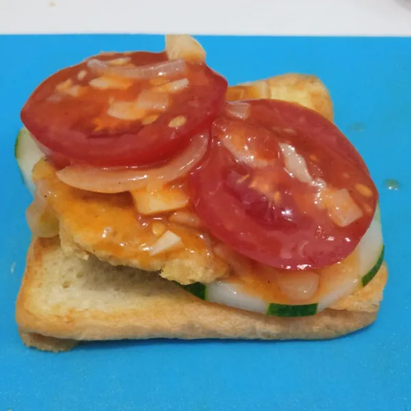 Siapkan roti. Letakkan timun, tempe, saus tomat, dan irisan tomat di atasnya. Kemudian tutup kembali dengan roti. Sajikan