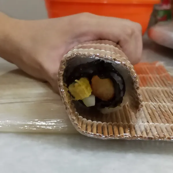 Lipat nori secara perlahan hingga membentuk bulat panjang (jangan terlalu di tekan di awal) dengan bamboo sushi roll