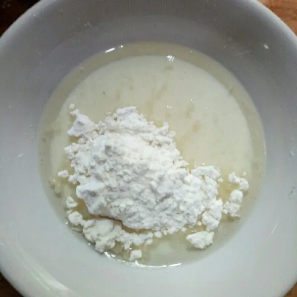 Masukkan tepung terigu ke campuran minyak dan susu lalu aduk hingga tercampur rata dengan whisk.