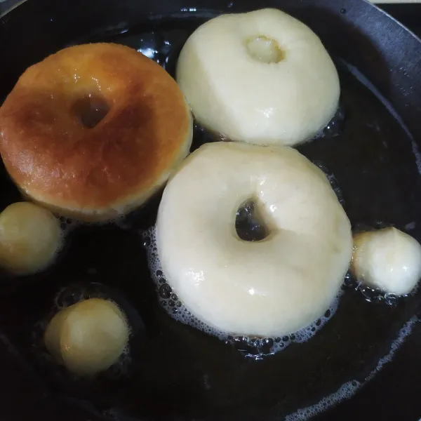 Panaskan minyak di teflon dengan api sangat kecil, lubangi donat dengan bantuan spuit, lalu goreng, setelah sisi bawah kecoklatan balik donat, goreng cukup sekali balikan saja agar tidak menyerap minyak, angkat dan tiriskan, lakukan hal yang sama untuk sisa donat.