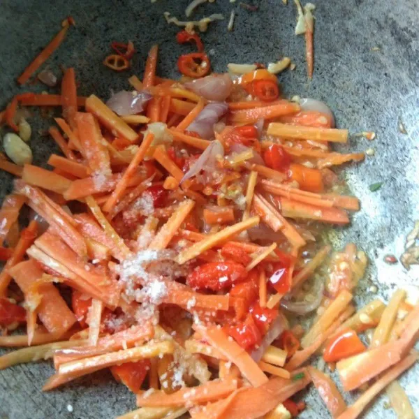 Masukkan irisan wortel. Tambahkan garam dan kaldu jamur. Aduk rata dan masak hingga wortel matang.