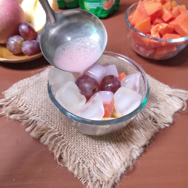 Tata buah-buahan dalam wadah saji, tuangkan air syrup.