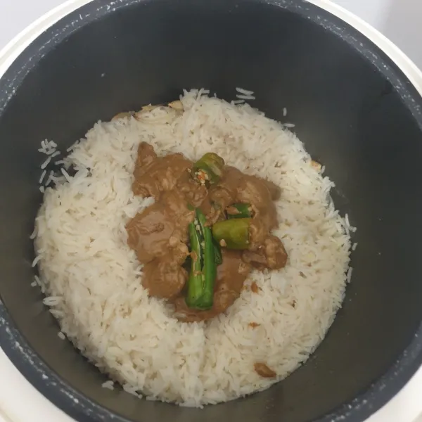 Masukan daging kambing kedalam nasi Aron, masukan juga cabe hijau. tutup bagian atasnya dengan nasi aron, dan masak nasi sampai matang.