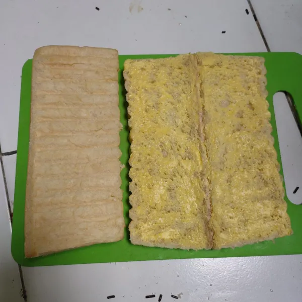 Oleskan mentega secara merata di bagian tengah roti.