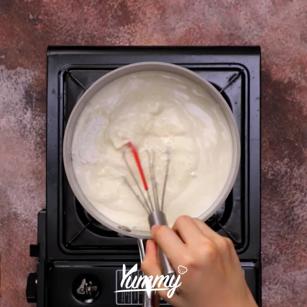 Dalam panci, panaskan susu cair, SKM, tepung maizena, dan essence vanilla hingga mendidih sembari terus diaduk.