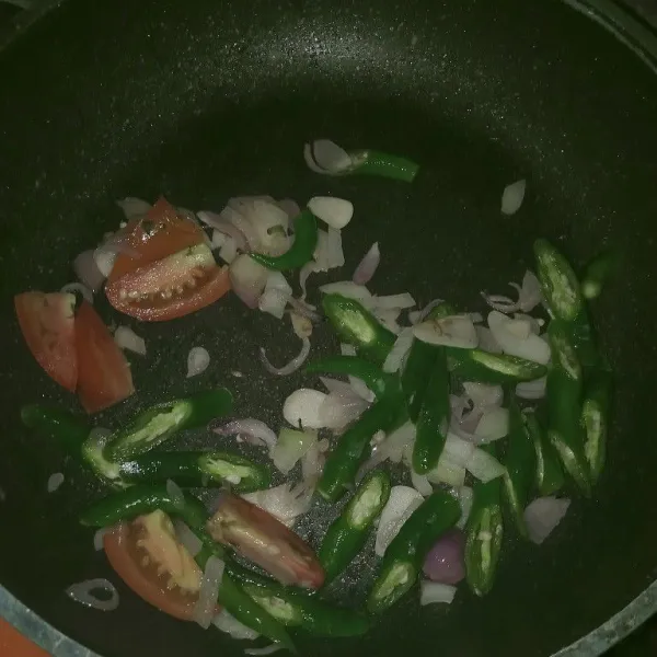 Tumis bawang putih dan bawang merah sampai harum. Masukkan cabai dan tomat, aduk sampai rata dan layu