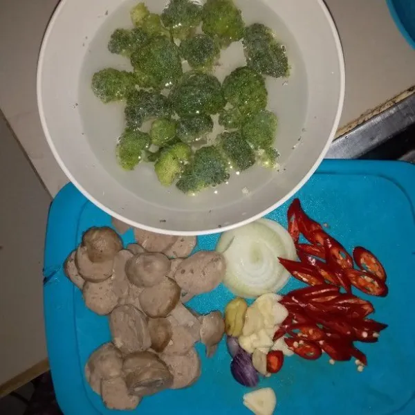 Potong brokoli per kuntum kemudian rendam dengan air garam lalu bilas. Potong bakso, cabai merah, bawang putih, bawang merah, dan bawang bombay sesuai selera.