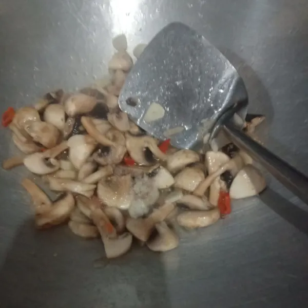 Lalu masukkan jamur kancing, tambahkan garam, lada bubuk, dan gula pasir. Tumis sampai berair
