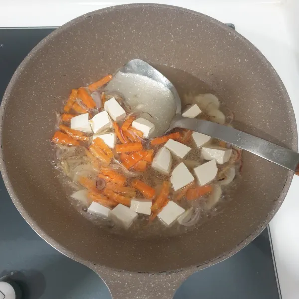 Masukan wortel, tahu dan tuangkan air, masak selama 3 menit.