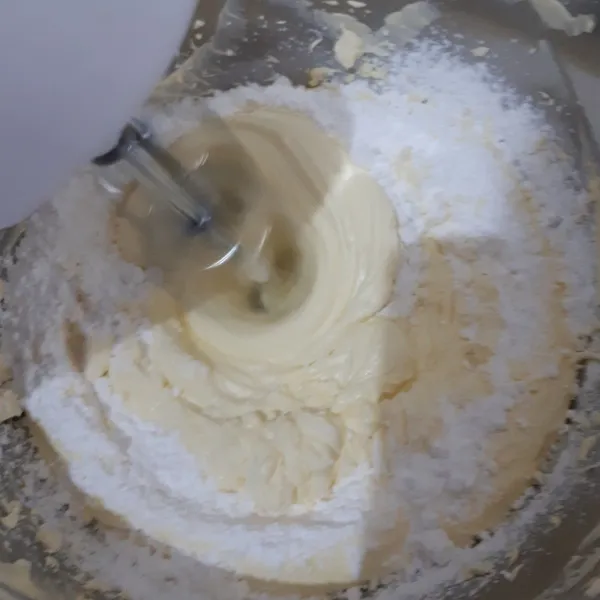 Kemudian masukkan gula halus sedikit demi sedikit, dan masukkan susu kental manis. Mixer sampai mengental.