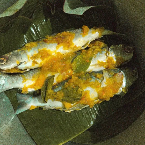 Tata ikan di dalam panci presto yang telah diberi alas daun pisang.