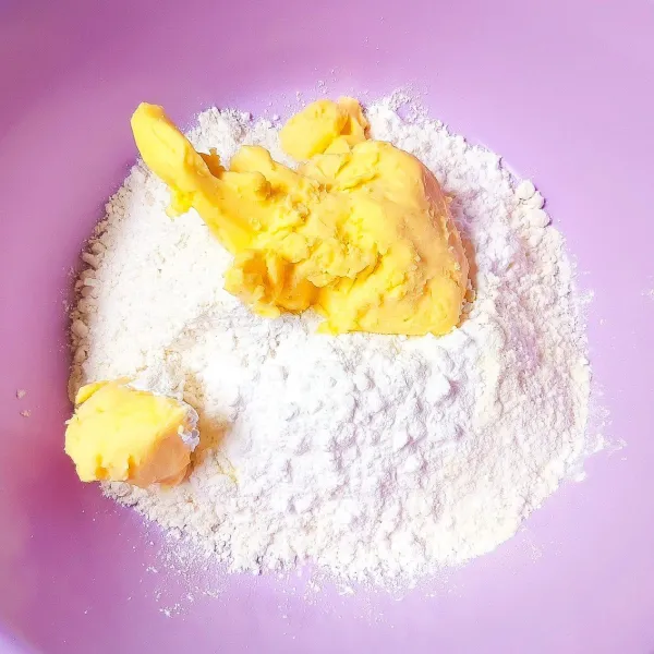 Siapkan wadah. Campurkan tepung terigu, susu bubuk, dan gula halus yang sudah diayak terlebih dahulu. Lalu tambahkan margarin dan remat menggunakan tangan sampai tercampur rata.