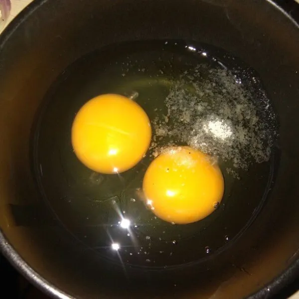 Dalam mangkok, pecahkan 2 telur beri kaldu bubuk lalu aduk rata.
