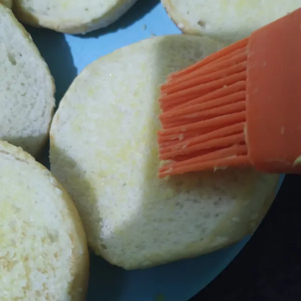 Oles roti bun dengan margarin di bagian depan dan belakang
