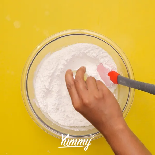 Tambahkan perisa vanila dan perisa pandan ke dalam campuran tepung lalu siram dengan air hangat.