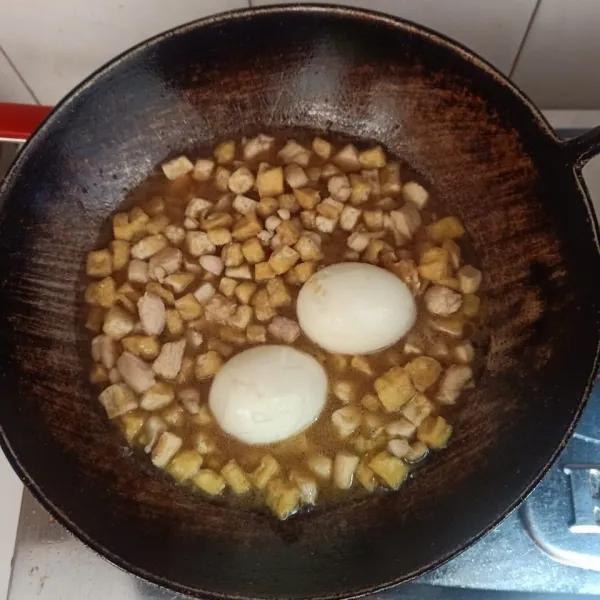 Masukkan tahu dan telur rebus, tambahkan air dan bumbu, angkat