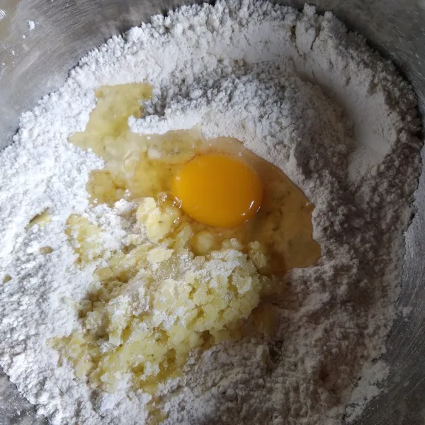Dalam wadah besar campur tepung terigu, gula pasir, kentang, dan telur. Aduk hingga berbulir.