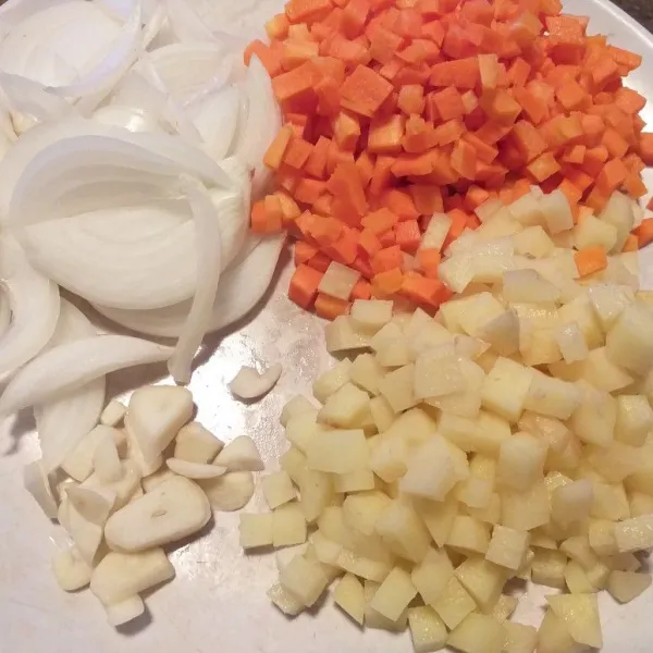 Pertama kita siapkan bahan-bahan, kupas wortel, kentang, bawang bombay dan bawang putih, cuci bersih kemudian untuk wortel dan kentang di potong dadu. Untuk bawang bombay diiris panjang, dan bawang putih di iris-iris, sisihkan.