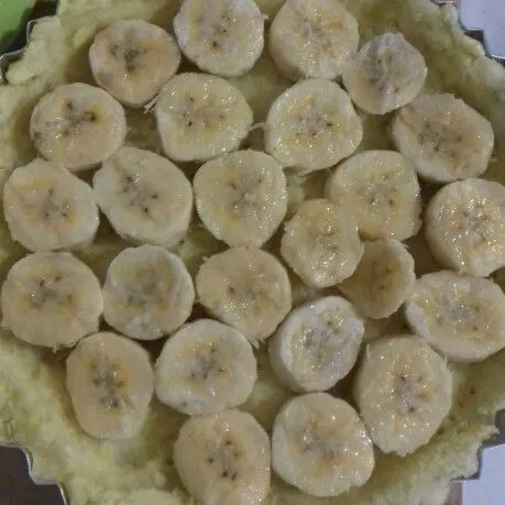 Keluarkan kulit pie dari oven. Tata pisang dipermukaan pie.