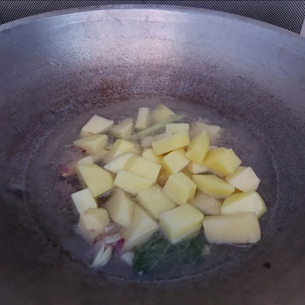 Masukkan air rebusan tetelan dan kentang. Tambahkan air bila dirasa kurang. Masak sampai kentang agak empuk.