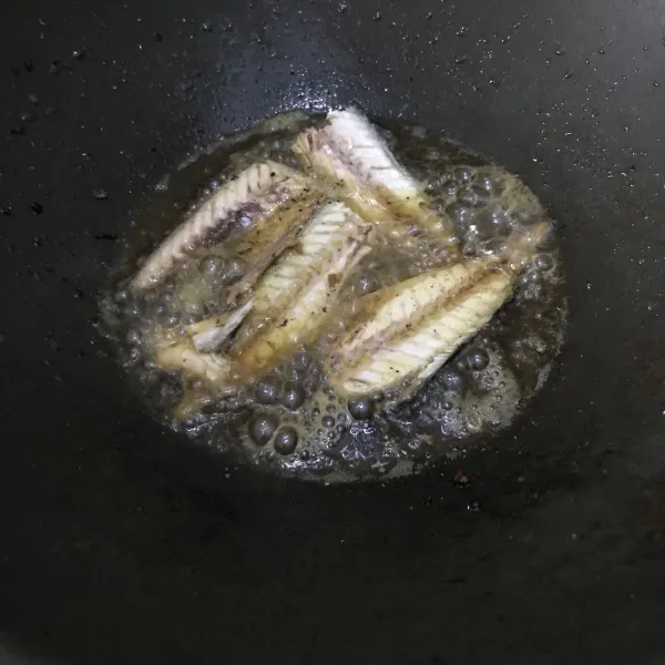 Potong ikan menjadi 4 bagian, hilangkan duri pada ikan kemudian goreng hingga setengah matang.