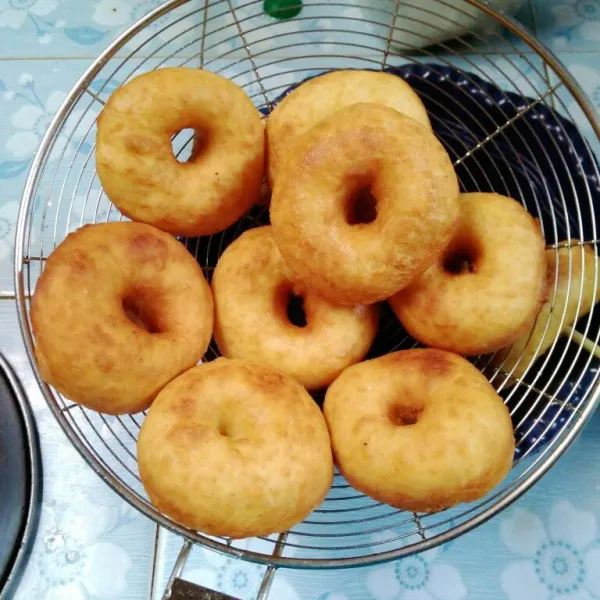 Lubangi dengan jari, kemudian goreng donat sampai kuning keemasan, gunakan api kecil. Tiriskan.