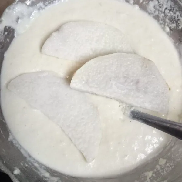 Masukkan potongan umbi uwi ke dalam adonan tepung. Baluri hingga rata.