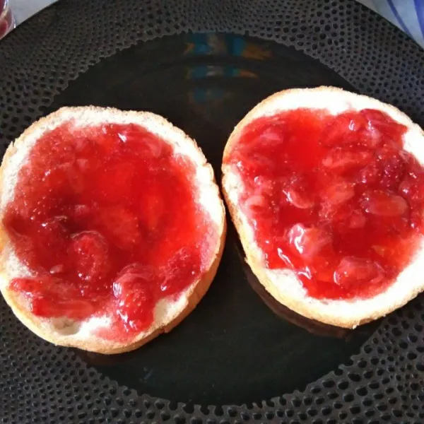 Siapkan piring saji tata 2 lembar rot, bagian bawah adalah bagian roti yang sudah dibakar, olesi atasnya dengan selai strawberry.