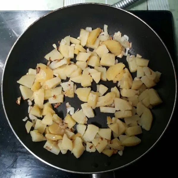 Tumis bawang bombay, bawang putih kemudian kentang yang sudah dipotong-potong, boleh menggunakan sedikit minyak.
