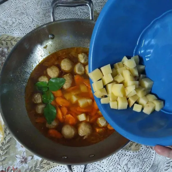 Masukkan daun jeruk dan kentang, masak sampai matang.