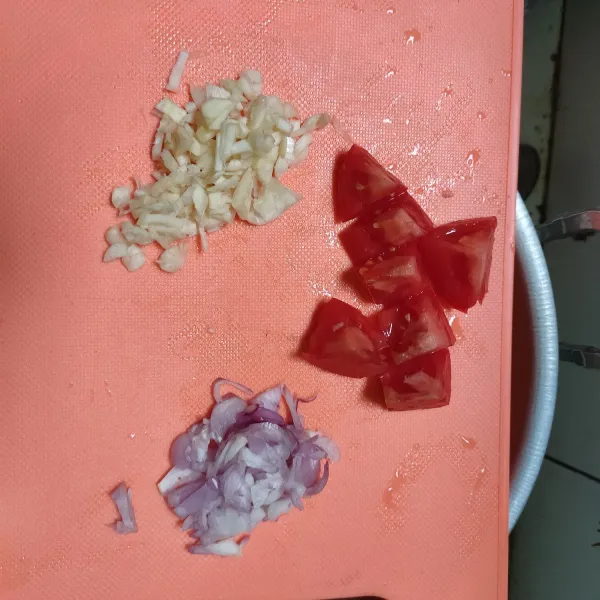 Cincang bawang putih dan bawang merah. Potong dadu tomat