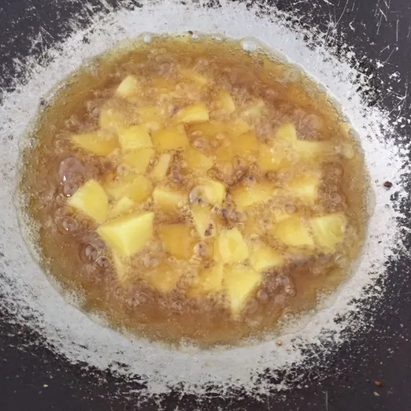 Potong dadu kentang yang sudah dicuci bersih dan dikupas, lalu panaskan minyak dan goreng hingga kuning keemasan, angkat dan tiriskan.