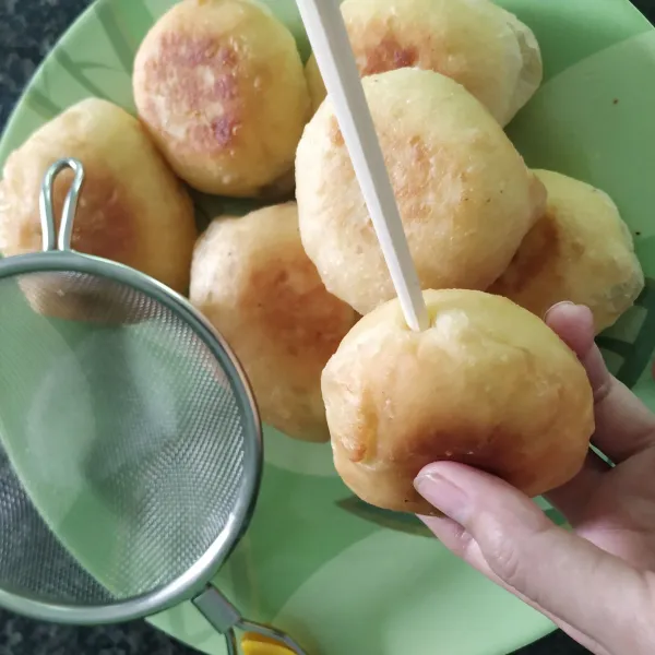 Tusuk tengah donat dengan sumpit.